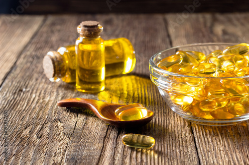 Fish oil capsules on wooden background, vitamin D supplement