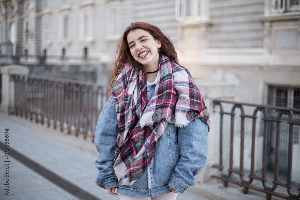 Attractive young girl in denim jacket and laughing on the street. 