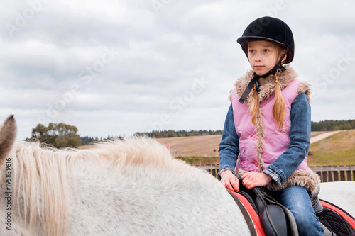 little girl riding a horse on a farm
