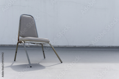 broken dead leather white chair on an outdoor concrete floor., with copy space for text.