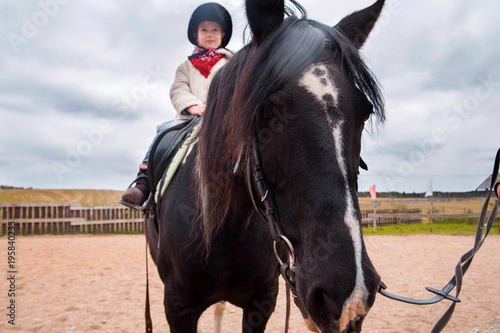little girl riding a horse on a farm