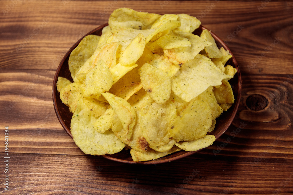 Plate of potato chips on wooden table Plate of potato chips on wooden table