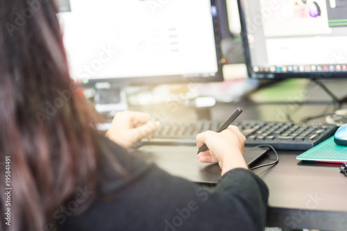 The woman was sitting design work in the office.And hand in capturing the mouse pen. In order to draw and use it as easily use it proficiently.