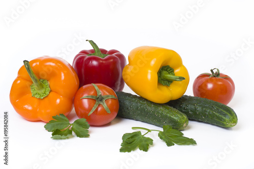Red yellow and orange peppers with tomatoes on a white background..Cucumbers with colorful peppers in composition on a white background.