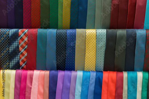Many colorful men ties hanging on shelves in store, background
