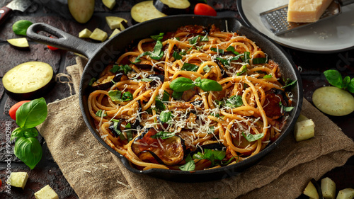 Vegetarian Italian Pasta Spaghetti alla Norma with eggplant, tomatoes, basil and parmesan cheese in rustic skillet pan. photo