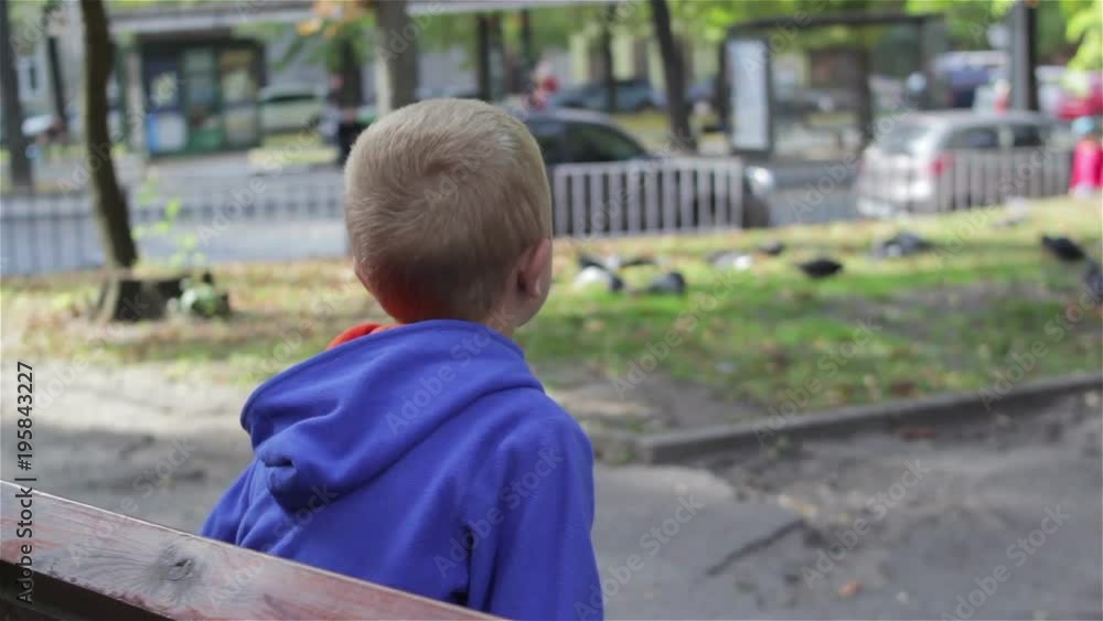 The boy was sitting on a bench in the spring The boy was sitting on a bench in the spring