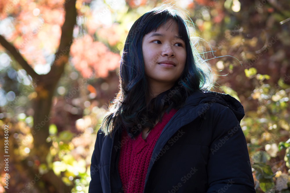 Young female posing in front of beautiful trees in Autumn when the leaves are red, orange and yellow Young female posing in front of beautiful trees in Autumn when the leaves are red, orange and yellow