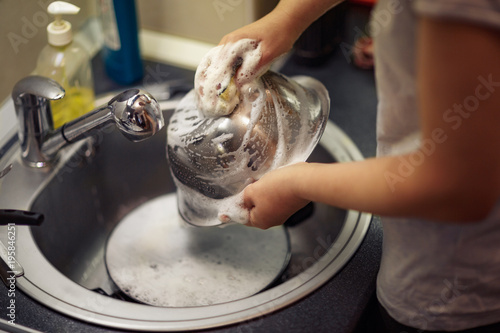 Man is washing the dishes in the kitchen .