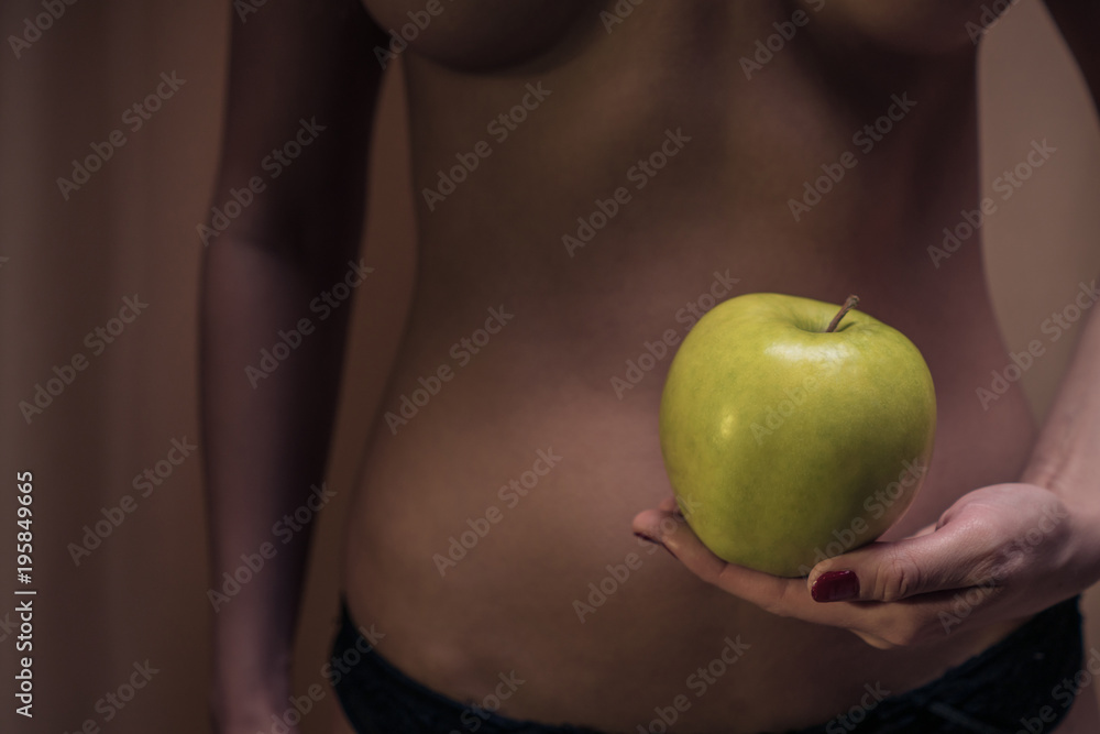 The concept of diet. Sexy female waist and an apple against the background of a woman's body. Healthy lifestyle The concept of diet. Sexy female waist and an apple against the background of a woman's body. Healthy lifestyle