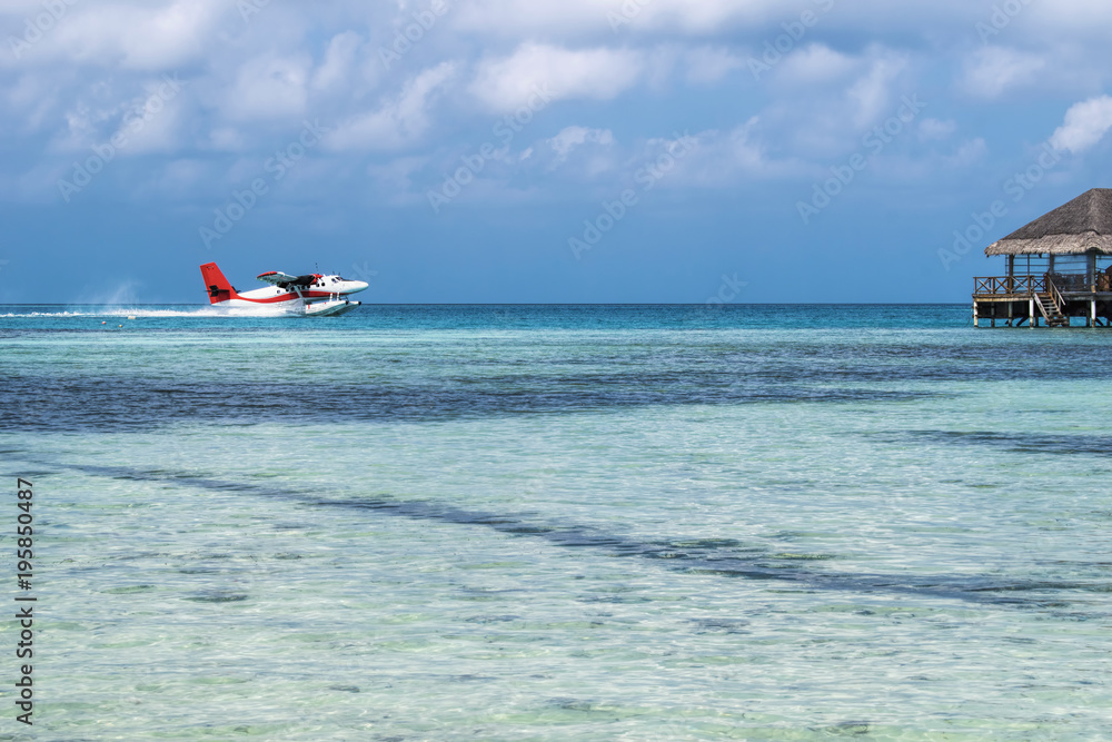 Seaplane landing in the ocean lagoon. Seaplane takeoff from the ocean beach at Maldives