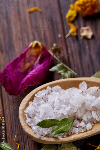 Composition of spa treatment on wooden background. Sea salt and flowers background, close up, top view, selective focus.