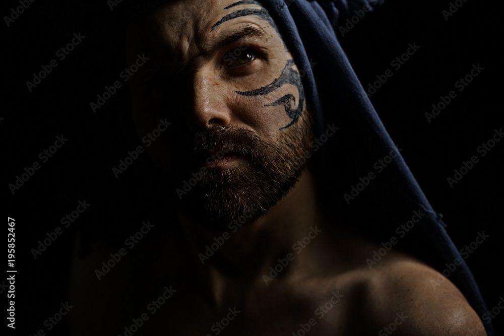 tattoo on the face, male portrait in the form of an assassin, cosplay, tattooed brutal man, guy with a tattooed face tattoo on the face, male portrait in the form of an assassin, cosplay, tattooed brutal man, guy with a tattooed face