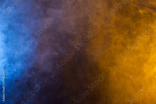Blueand yellow smoke in dark background. Texture and desktop picture