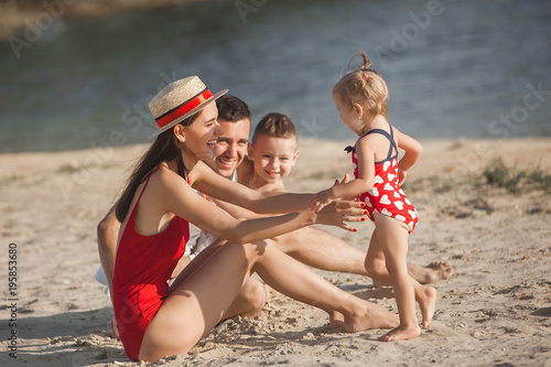 Happy family having fun at the beach. Mom, dad, son and little daughter at the sea shore. Cheerful family