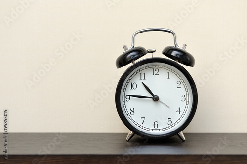 Classic black alarm clock in the home on a wall background