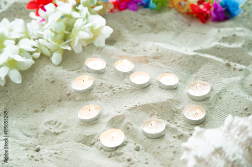 set of candles in form of heart on the sand with flowers