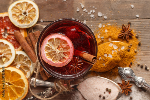Mulled wine, spices and dried fruits on a rustic table.