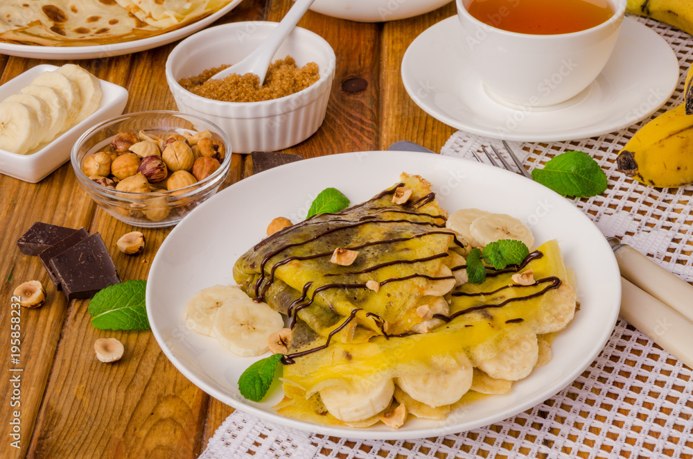 Crepes or pancakes with chocolate cream, bananas and hazelnuts for breakfast Crepes or pancakes with chocolate cream, bananas and hazelnuts for breakfast