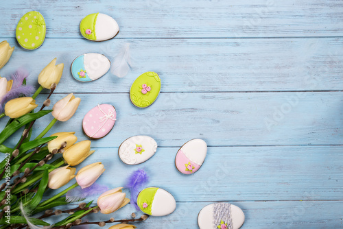 Colorful easter cookies and tulips on blue wooden background
