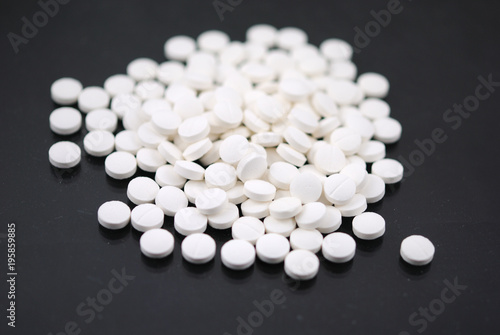 White round tablets closeup on black background