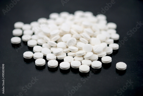 White round tablets closeup on black background