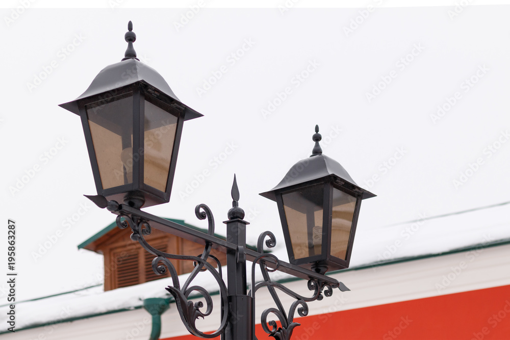 Wrought iron lantern with patterns on the background of the red building and the sky