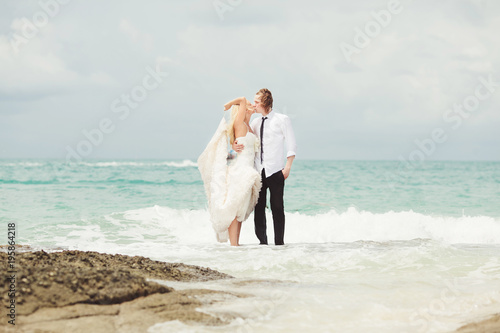 bride and groom kissing at the sea. couple in love on deserted beach.