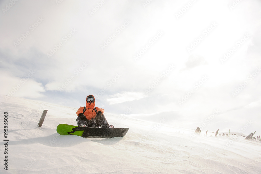Snowboarder sitting on snow in Goderdzi, Georgia