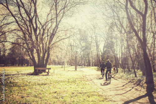 mature couple is cycling at the park vintage effect  two adults are riding a bicycle 