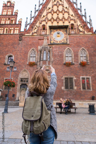 A woman traveler takes pictures of a landmark by phone camera. © scharfsinn86