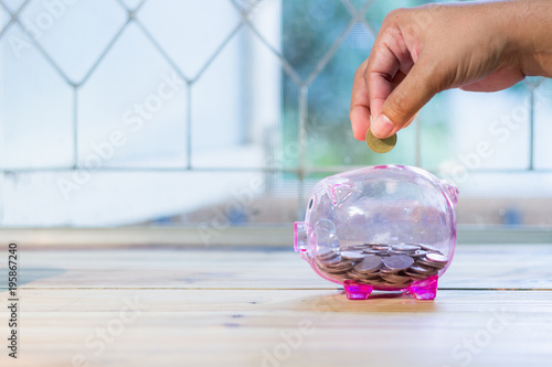 Pink piggy bank has coin inside. There are men's hands are coin. , The concept of saving money for the future