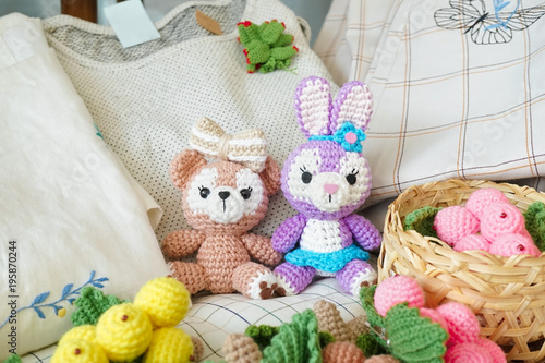 crochet dolls. a cute teddy bear and Easter bunny amigurumi doll, are sitting together with other crochet fruits at the weekend market.
