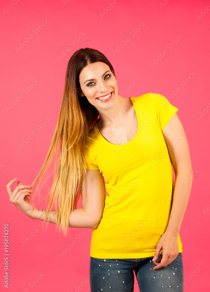 Funky young woman in yellow t shirt pose over pink background Funky young woman in yellow t shirt pose over pink background