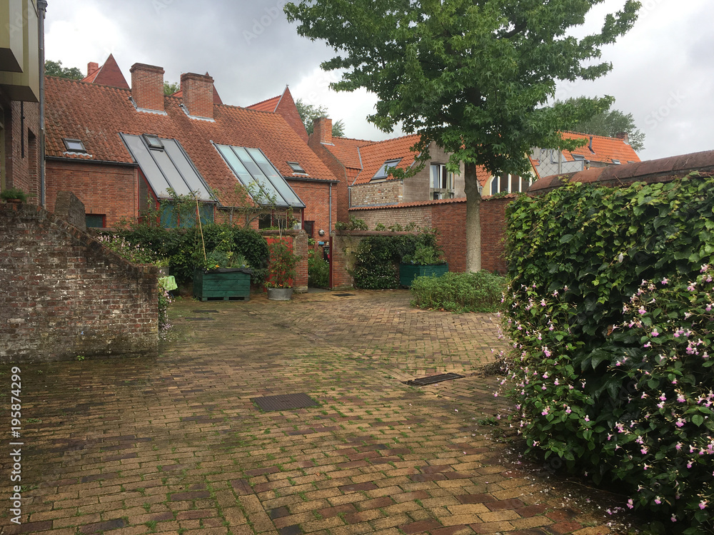 Typical vernacular housing in Antwerp Belgium. Small stone residential housing in Belgium. Cobblestone pavings, small garden, stone front steps. Residential housing in Antwerp. Typical vernacular housing in Antwerp Belgium. Small stone residential housing in Belgium. Cobblestone pavings, small garden, stone front steps. Residential housing in Antwerp.