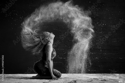 girl in a cloud of dust outlines an arc wave of hair. black and white photo