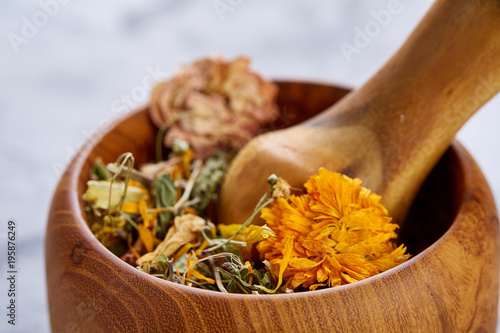 Spa still life with flowers in wooden bowl on light textured background, top view, close-up, selective focus photo