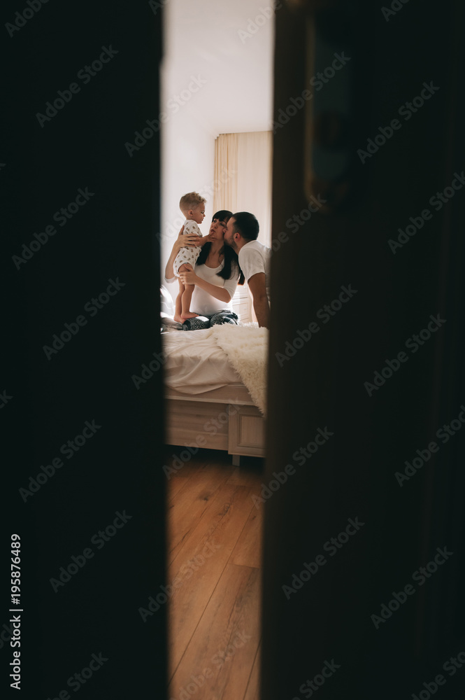 A pregnant mother kisses her son, and his father hugs him