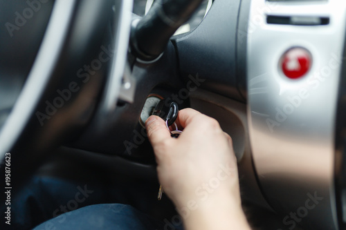 The driver of the man gets a car with a key. The hand inserts the key into the ignition and starts the car. Hand put the car key to the keyhole starting the car. © korchemkin