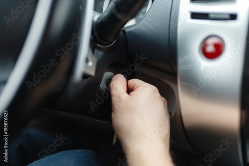 The driver of the man gets a car with a key. The hand inserts the key into the ignition and starts the car. Hand put the car key to the keyhole starting the car.