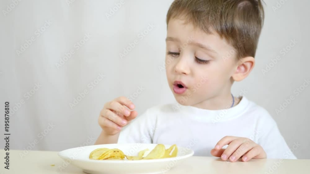 Child boy eating potato chips on a white background. Child boy eating potato chips on a white background.
