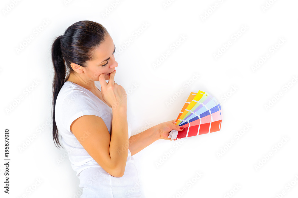 girl with a dreamy look chooses the color of the paint to repair the room, on a white background girl with a dreamy look chooses the color of the paint to repair the room, on a white background