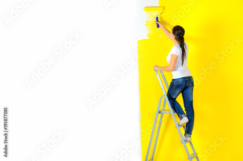 Obraz na płótnie girl painter paints a wall with a platen standing on a staircase w salonie