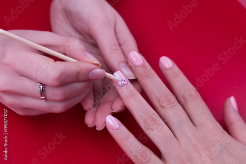 drawing rhinestones on the nail. a young manicurist