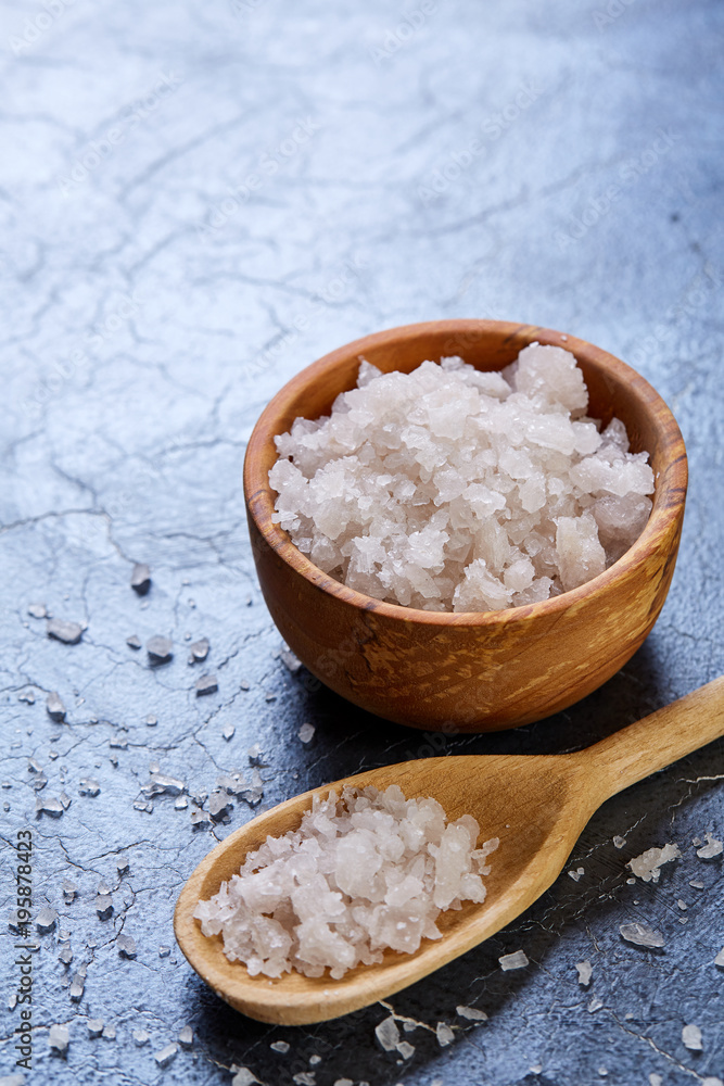 Large white sea salt in a natural wooden bowl on dark background, top view, close-up, selective focus Large white sea salt in a natural wooden bowl on dark background, top view, close-up, selective focus