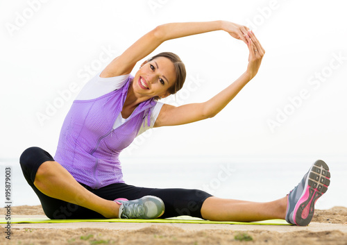 Woman training yoga poses sitting on beach