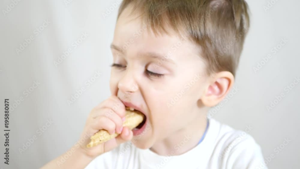 The child eats a chocolate cone of ice cream in a waffle cone, sitting at a table. The child eats a chocolate cone of ice cream in a waffle cone, sitting at a table.