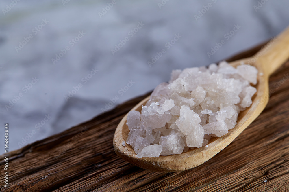 Crystal sea salt in a wooden spoon on dark vintage wooden background, top view, close-up, selective focus. Crystal sea salt in a wooden spoon on dark vintage wooden background, top view, close-up, selective focus.