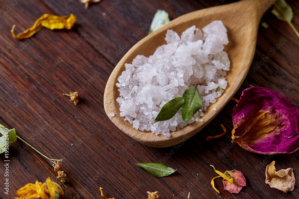 SPA concept: composition of spa treatment with natural sea salt, aromatic oil and flowers on wooden background SPA concept: composition of spa treatment with natural sea salt, aromatic oil and flowers on wooden background