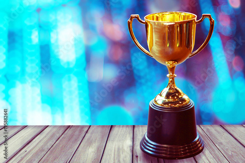 Chamption trophy on wood table with abstract bokeh light background, win concept. photo